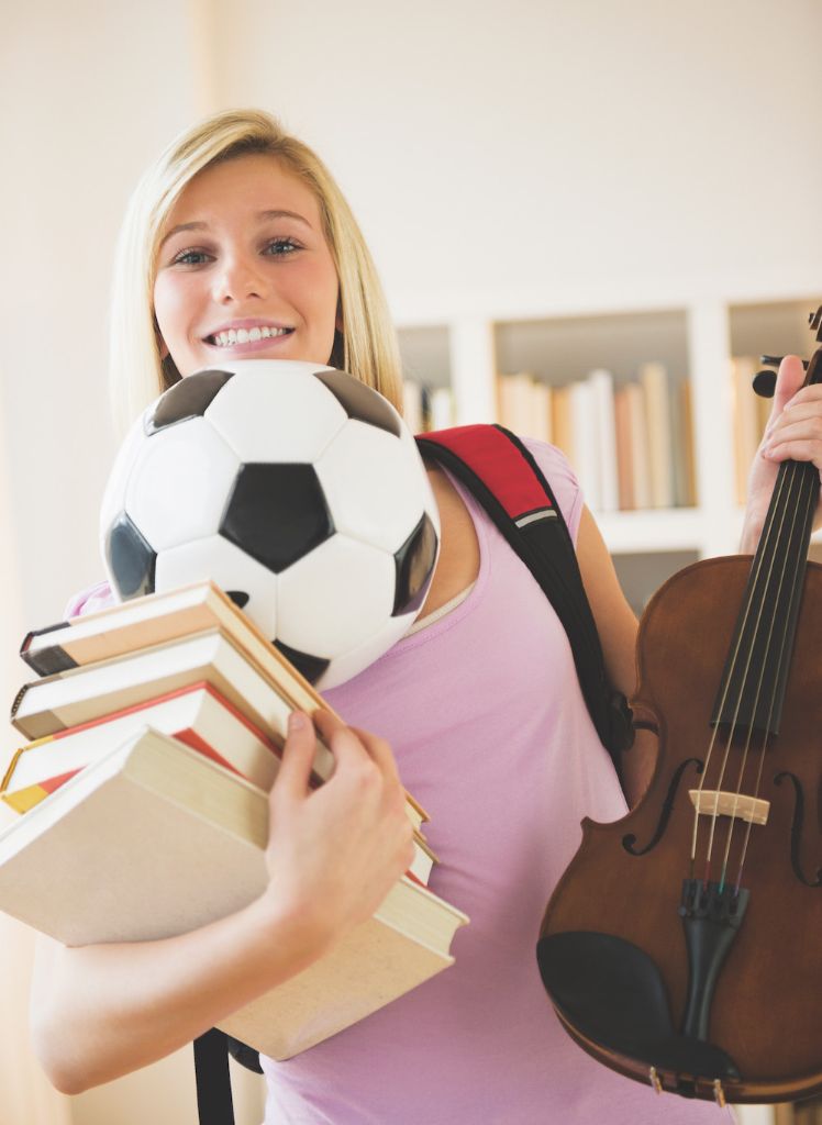 Getting the right balance Teen balancing books, soccer ball and violin